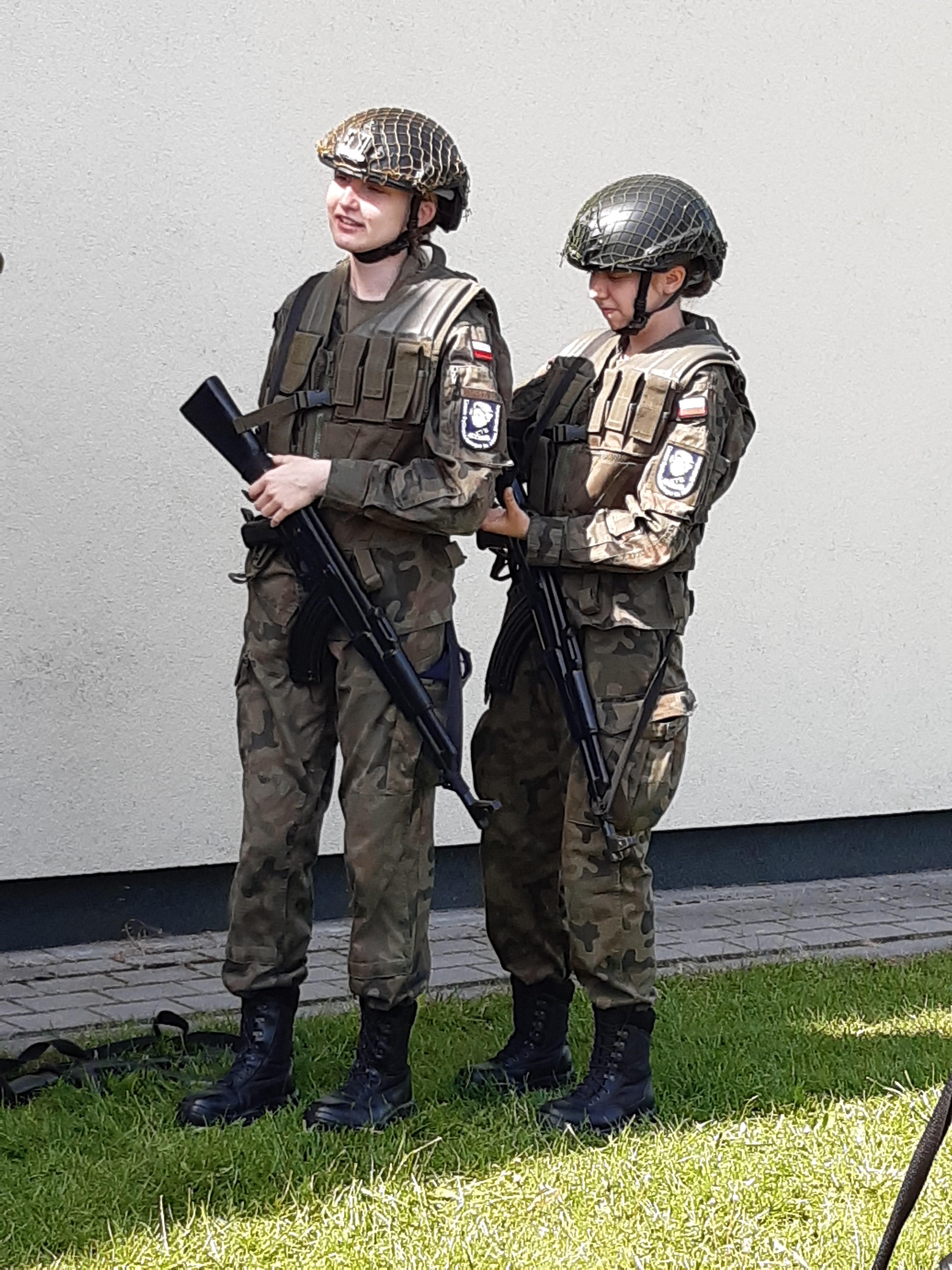 Dwie uczennice w pełnym umundurowaniu i z bronią podczas zajęć z taktyki wojskowej